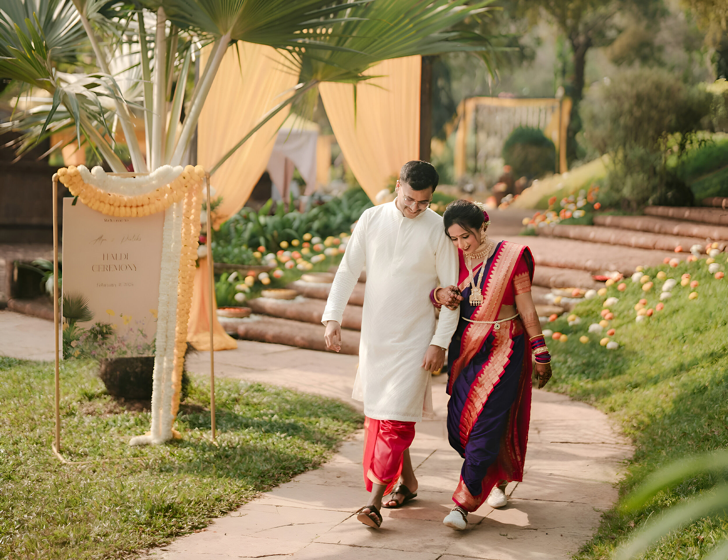 Newlyweds dressed in traditional wedding attire, walking together at a breathtaking destination wedding venue